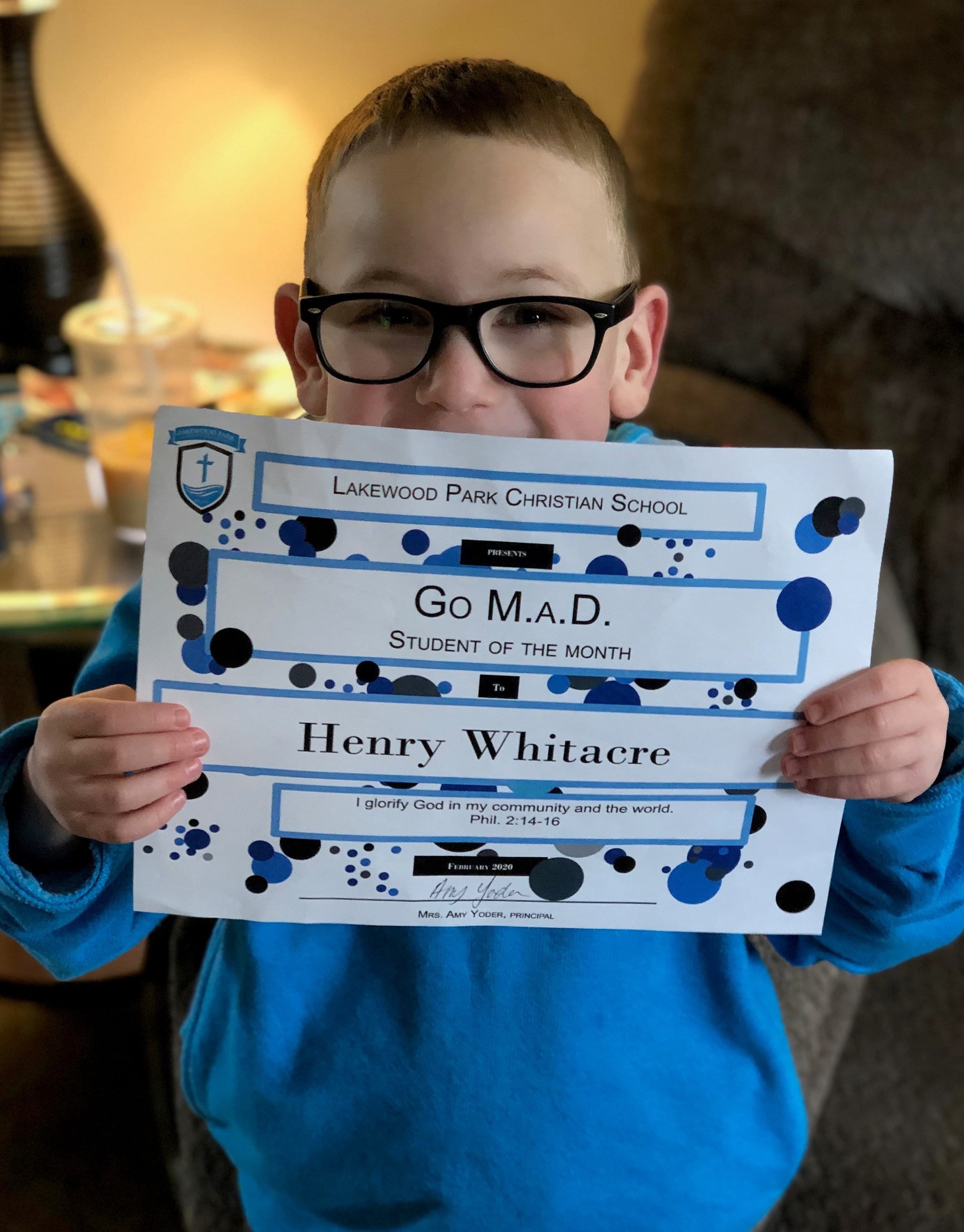 Henry holds up "Student Of The Month" Award
