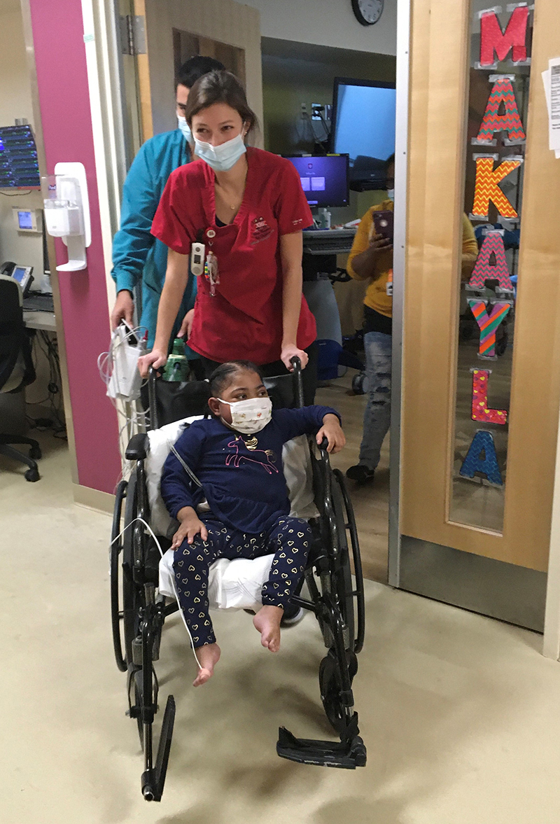 Makayla gets pushed in her wheelchair throughout the Riley halls