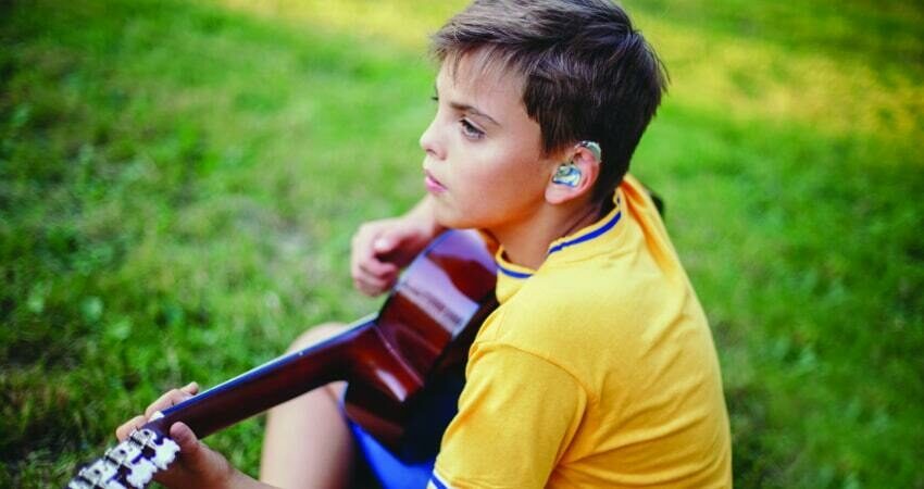 child with hearing aid playing instrument